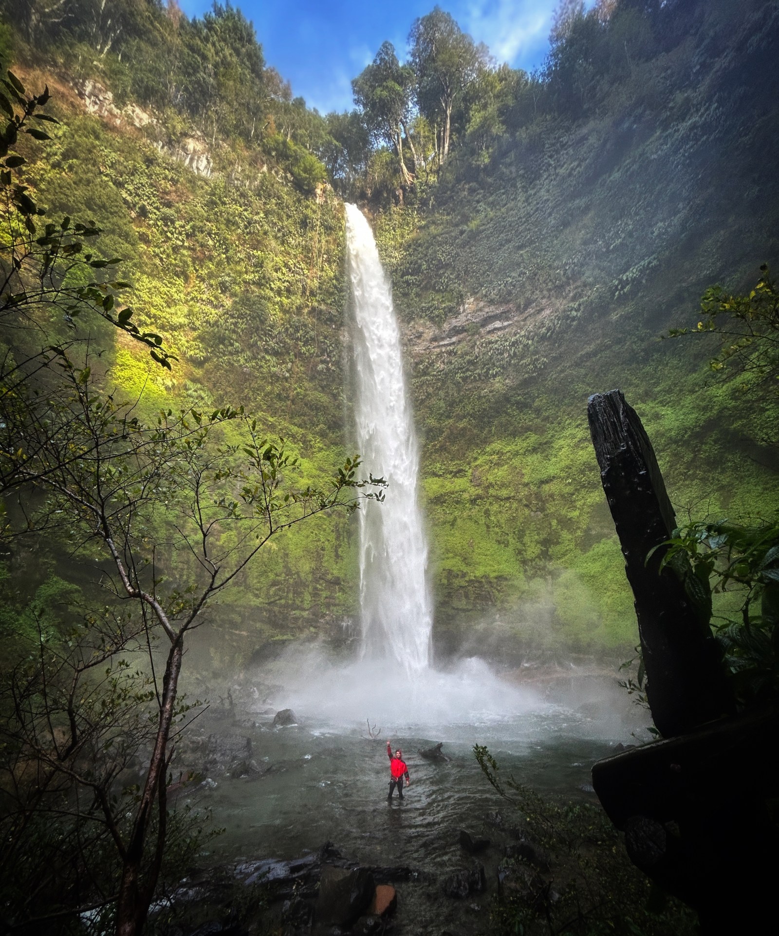 Caída completa del Salto El Claro con una persona de rojo al pie de la cascada