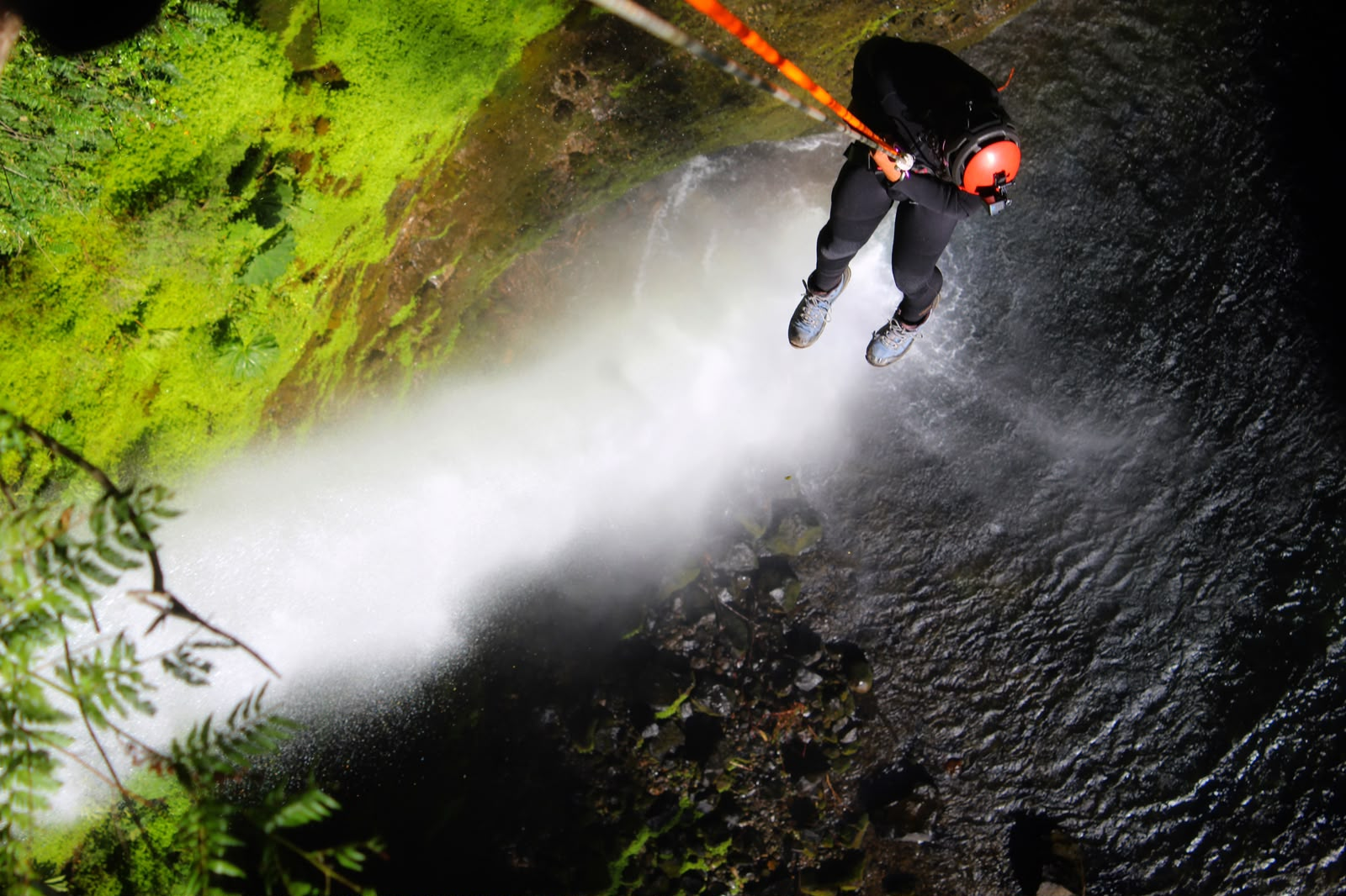 Vista cenital de una rapelista suspendida sobre la cascada del Salto El Claro