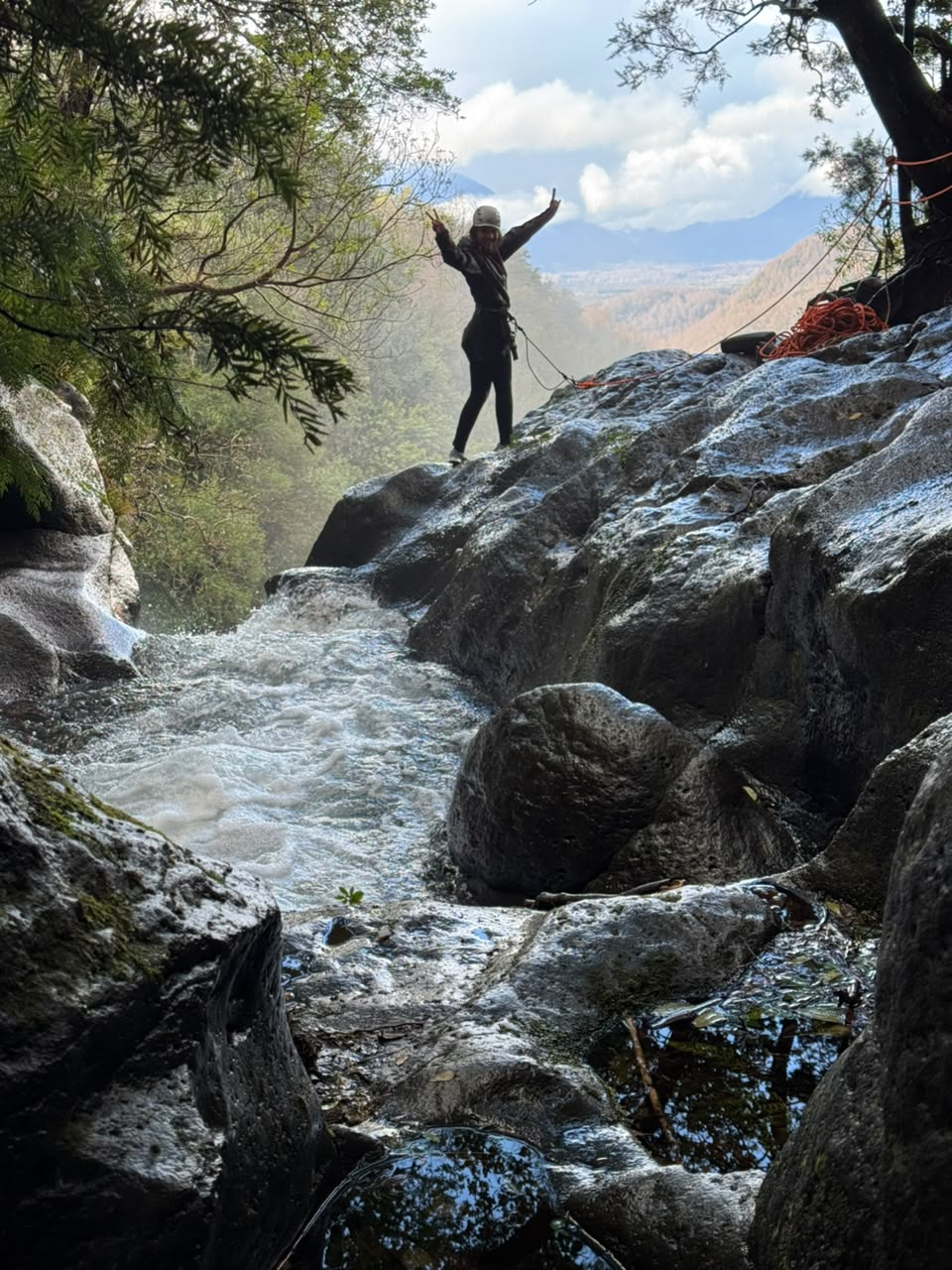 Aventurera celebrando sobre una roca del cañón con el Volcán Villarrica al fondo