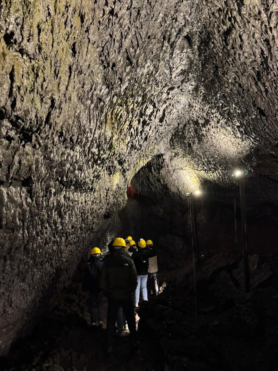 Grupo con cascos amarillos avanzando bajo la bóveda de un extenso túnel de lava
