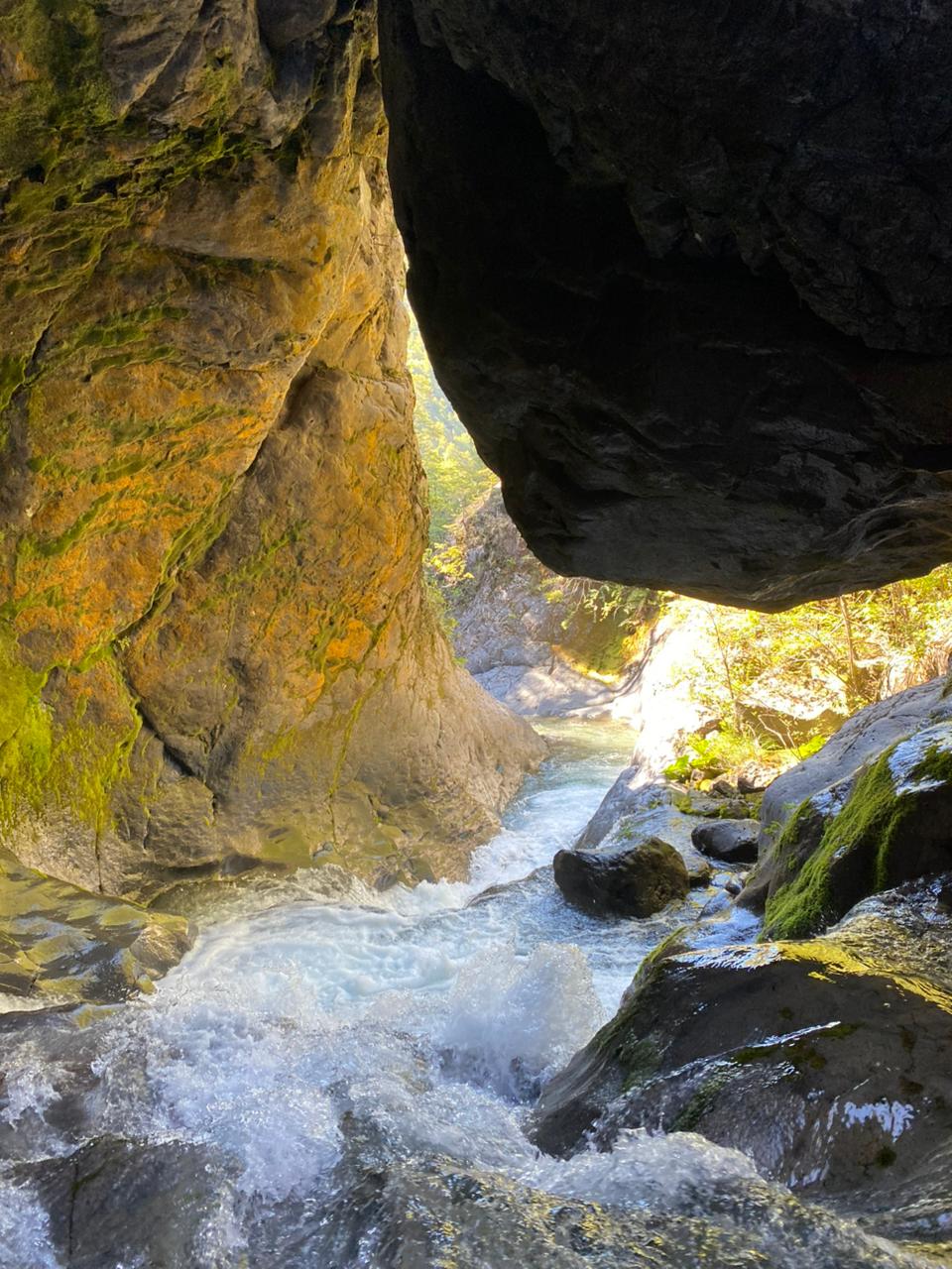 Interior del cañón El Pillán con un bloque de roca suspendido sobre el agua y luz entrando por la garganta